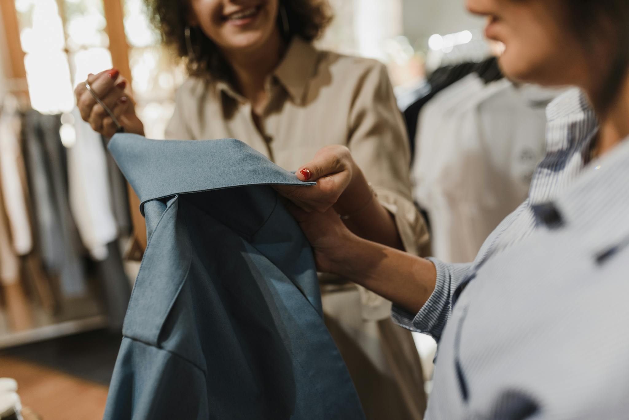Women examining a blue garment in a modern boutique, highlighting a shopping experience.